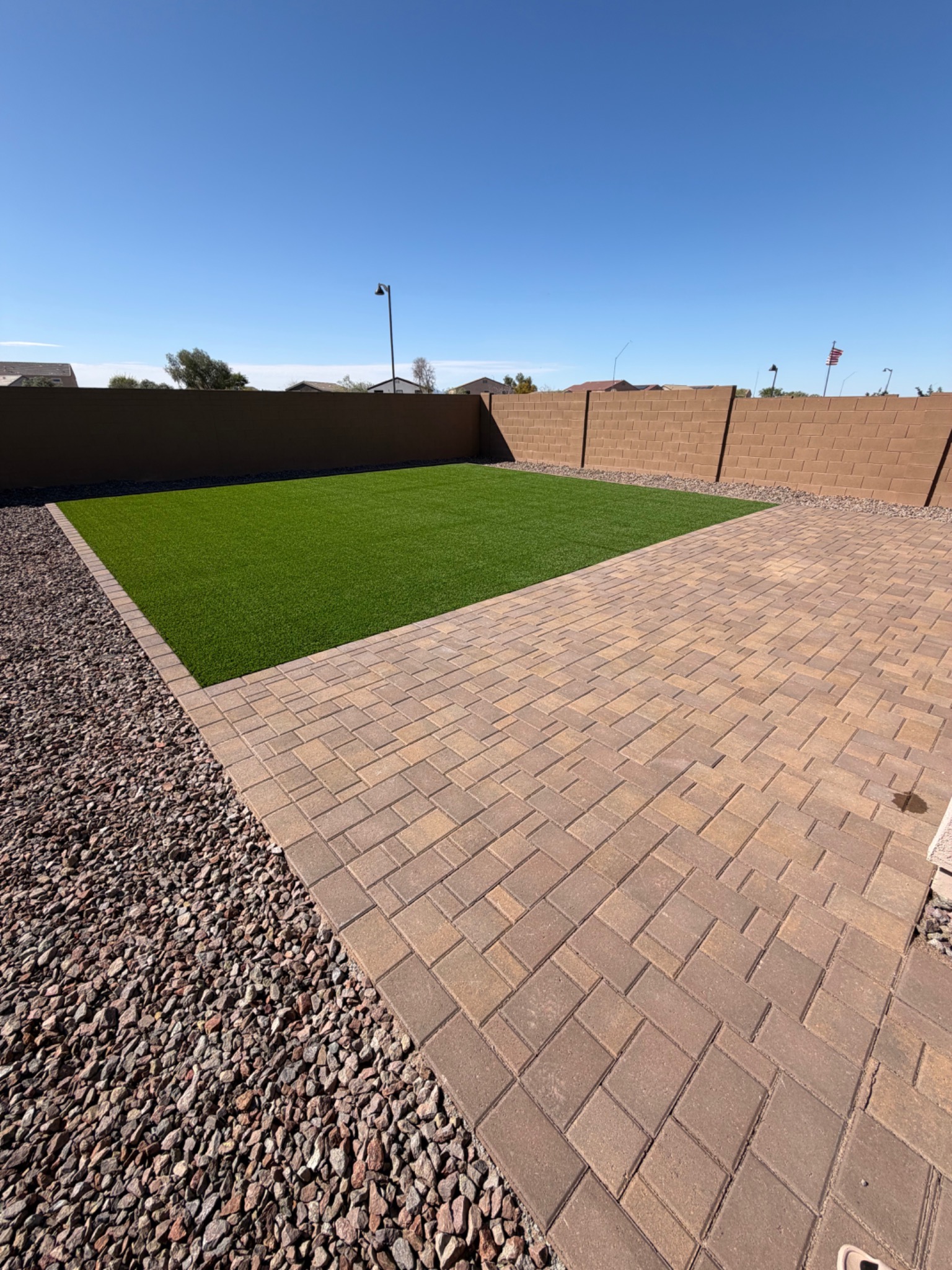 Artificial turf lawn beside a paver entertaining patio